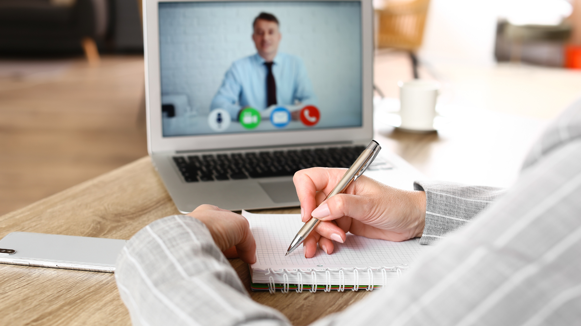 A student taking notes on introduction phrases during a video call with a teacher in an online English lesson.